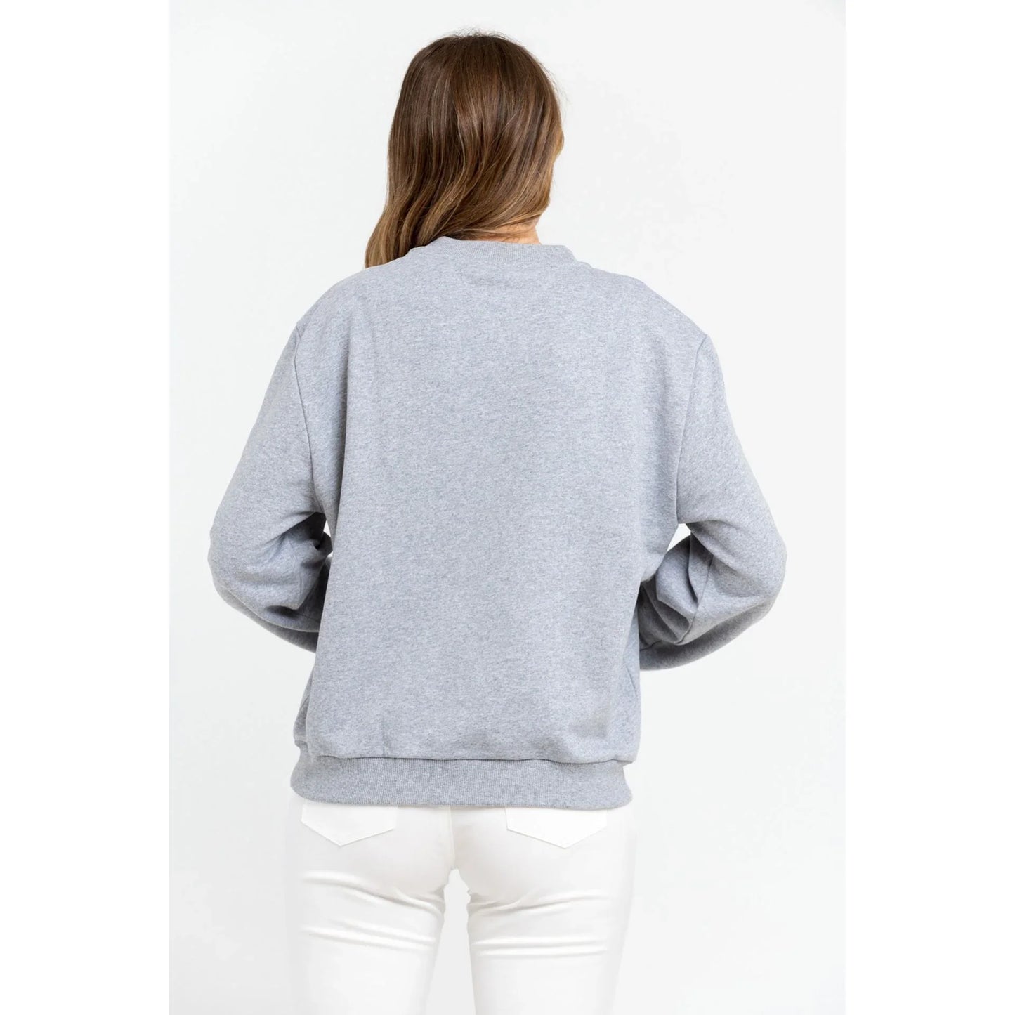 Donna di spalle con felpa grigia oversize e pantaloni bianchi, moda casual donna.