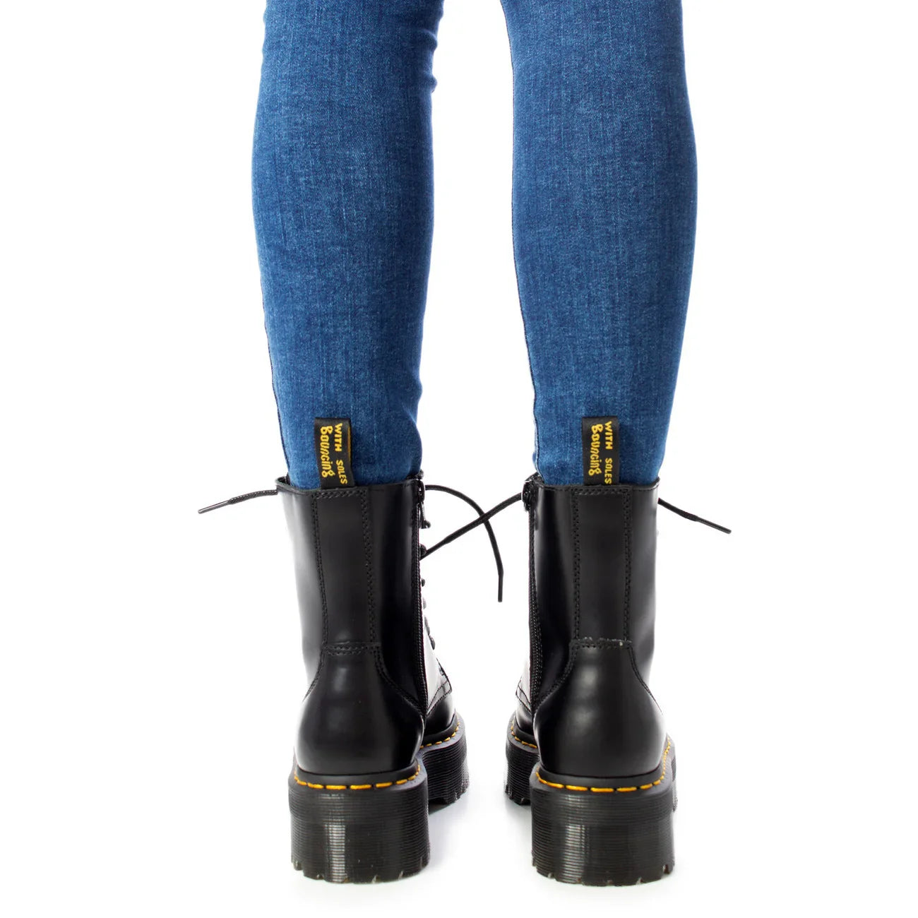 Stivaletti anfibi neri in pelle con suola alta e pantaloni jeans donna, vista posteriore.
