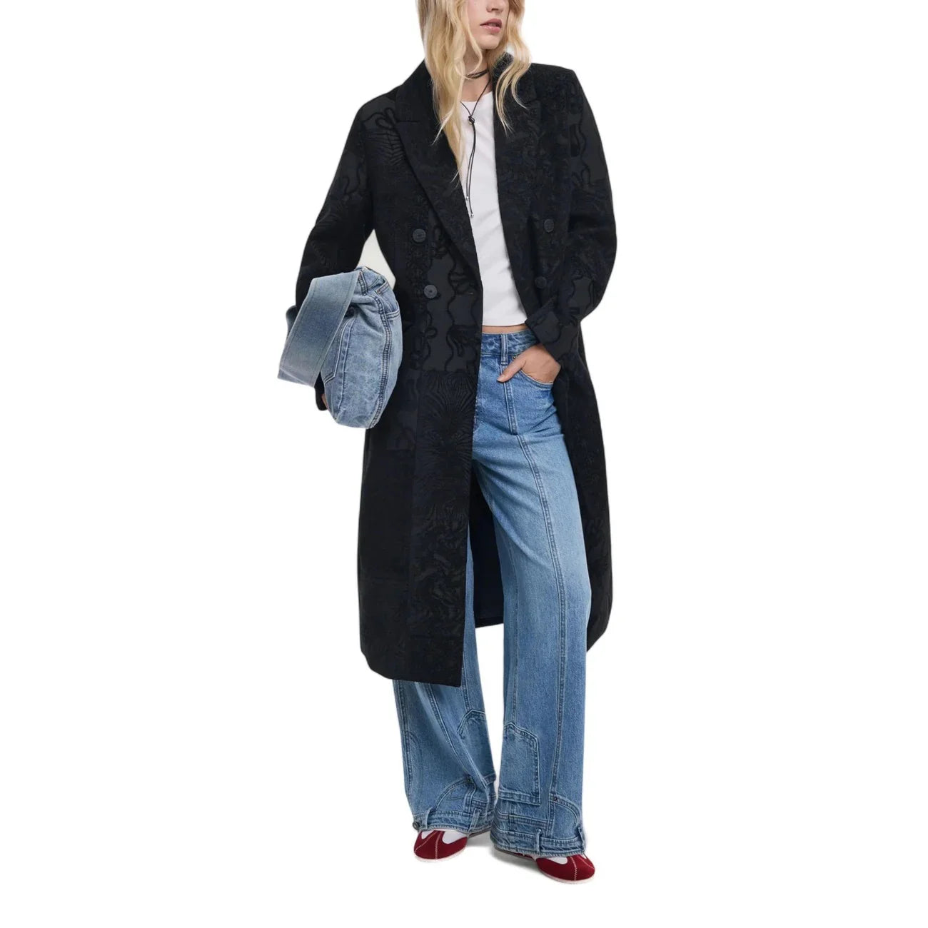 Donna con cappotto nero elegante, jeans larghi, t-shirt bianca, scarpe rosse moda casual