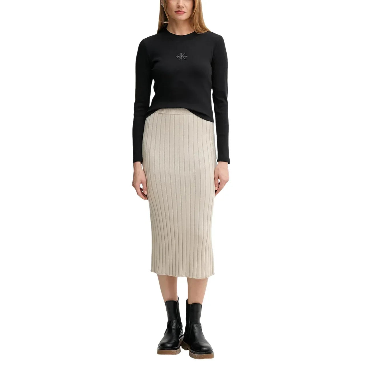 Donna con maglia nera a maniche lunghe, gonna lunga beige a costine e stivaletti neri
