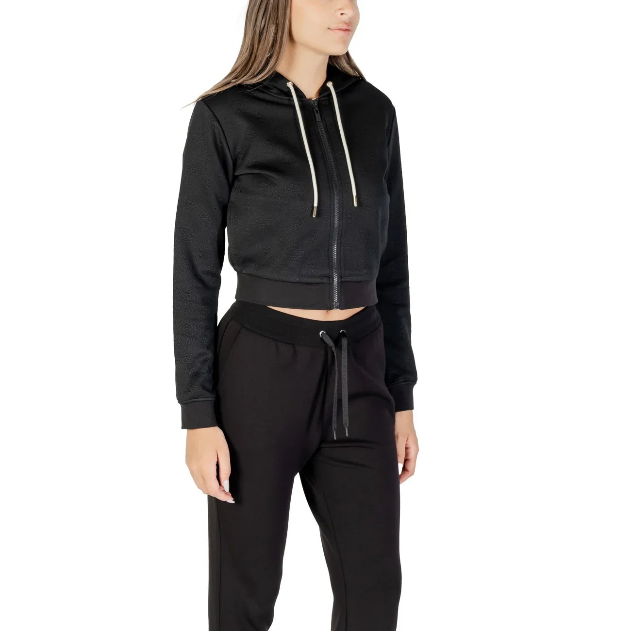Donna con felpa nera corta con cappuccio e pantaloni sportivi neri, moda casual