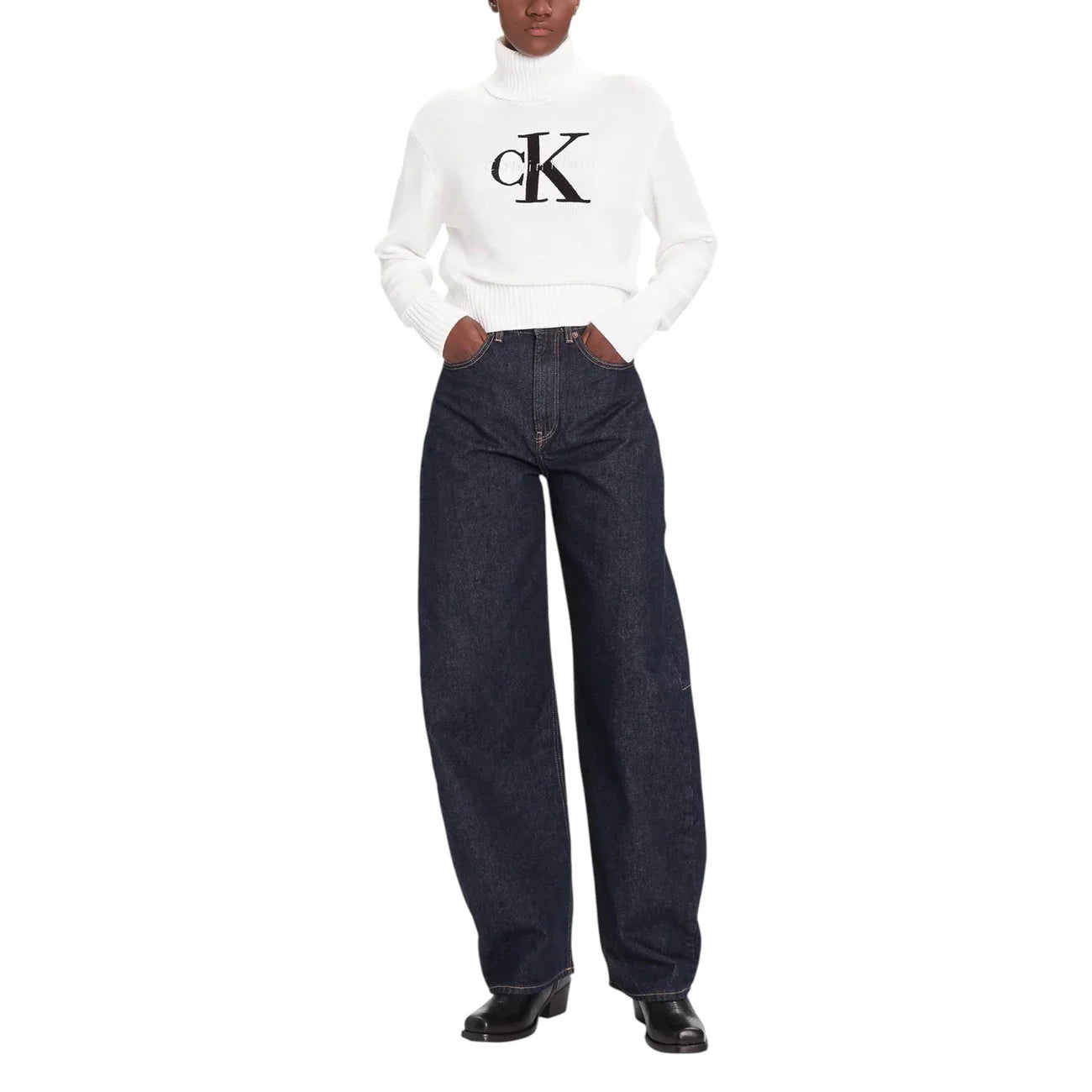 Donna con maglione bianco a collo alto e jeans larghi blu, look moda donna casual.