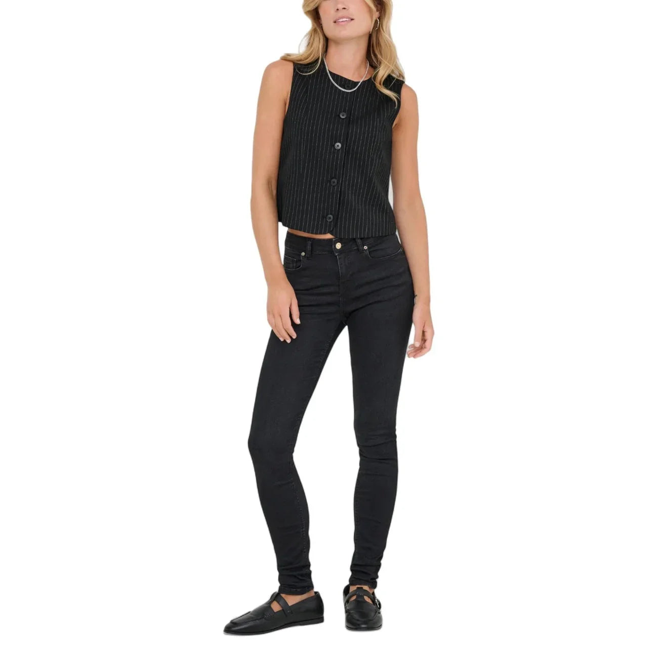 Donna con gilet nero senza maniche, jeans skinny neri e scarpe eleganti, moda donna casual